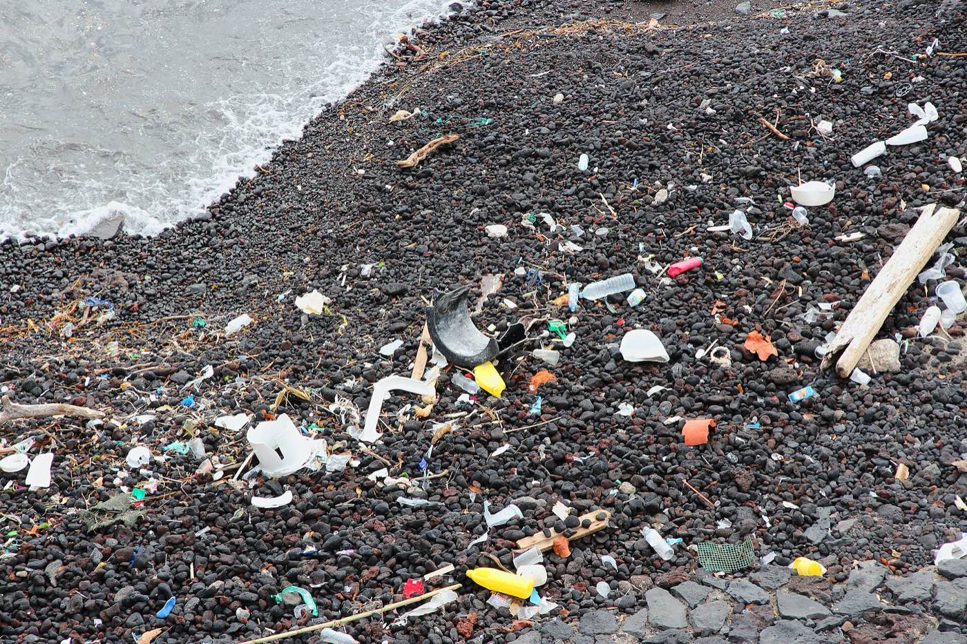 Plastic debris and rubbish washed up across a black stone beach in Tenerife